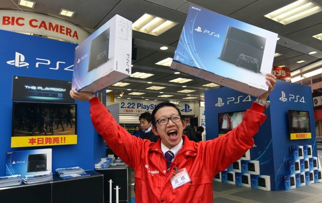 Vendedor japonés mostrando eufórico dos cajas de PS4