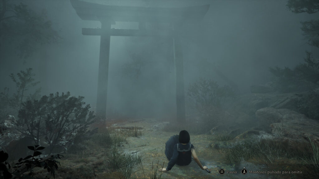 Una persona sentada (Hinako) en un camino brumoso, frente a una alta y sombría puerta torii rodeada de denso follaje, lo que crea una atmósfera misteriosa e inquietante.